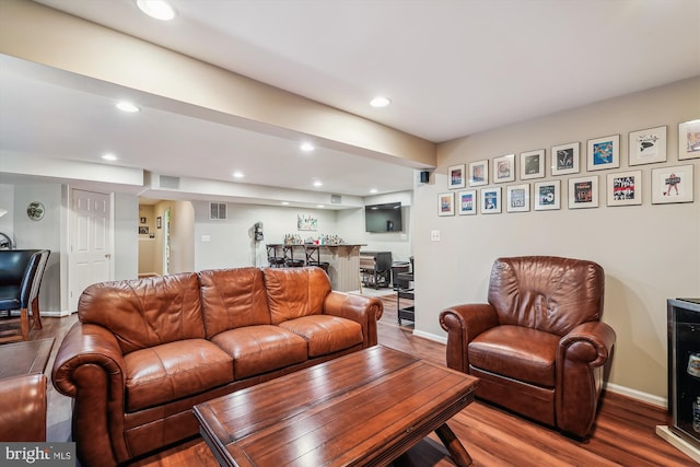 living area featuring bar, recessed lighting, wood finished floors, and baseboards