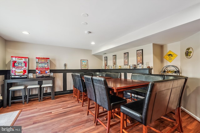 dining area with a bar, recessed lighting, and wood finished floors