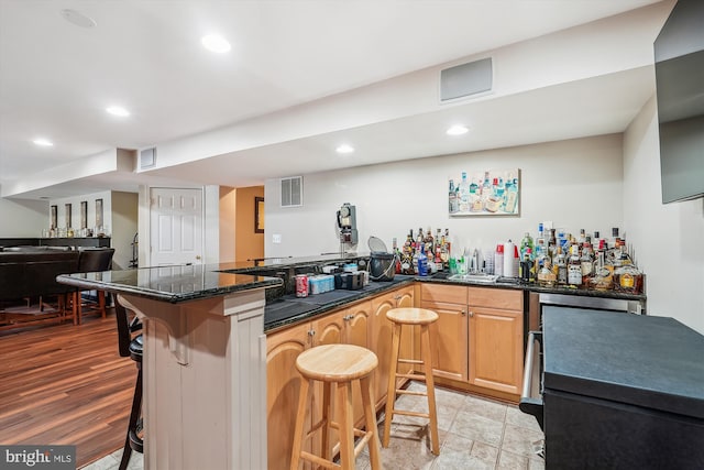 kitchen with a peninsula, a kitchen breakfast bar, recessed lighting, and visible vents