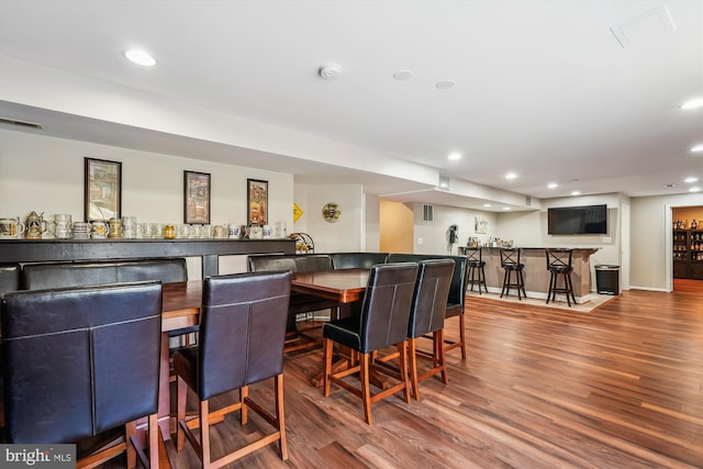 dining area with recessed lighting, indoor wet bar, and wood finished floors