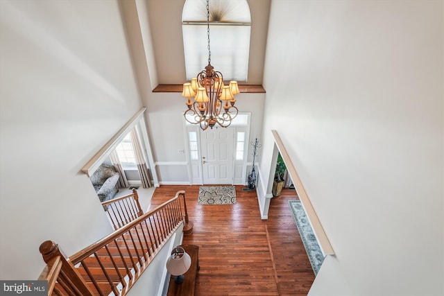 foyer featuring baseboards, stairs, a towering ceiling, wood finished floors, and a notable chandelier