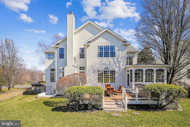 back of house with fence, a wooden deck, a yard, a sunroom, and a chimney