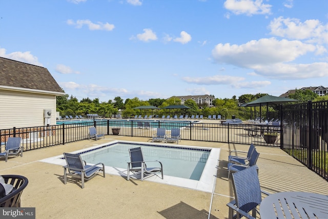 community pool with a patio area and fence