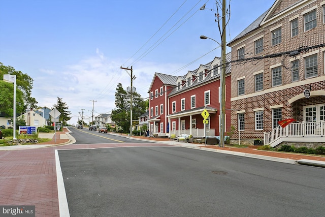 view of road featuring traffic signs, street lighting, sidewalks, and a residential view