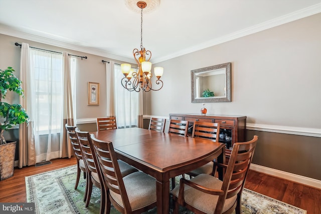 dining space with an inviting chandelier, crown molding, wood finished floors, and baseboards