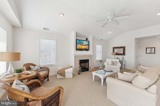 living room featuring a wealth of natural light, a tiled fireplace, a ceiling fan, and vaulted ceiling