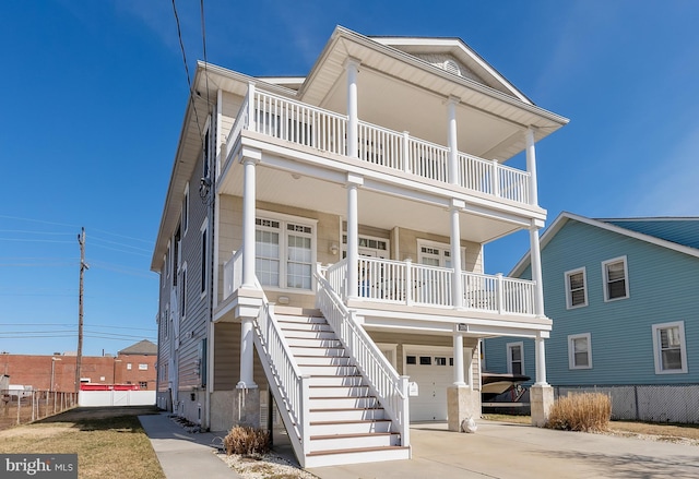 view of front of house featuring stairway, covered porch, an attached garage, and driveway