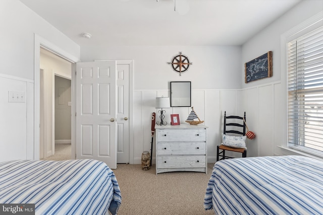 carpeted bedroom with a wainscoted wall and multiple windows