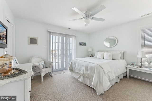 bedroom with access to outside, light colored carpet, visible vents, and ceiling fan