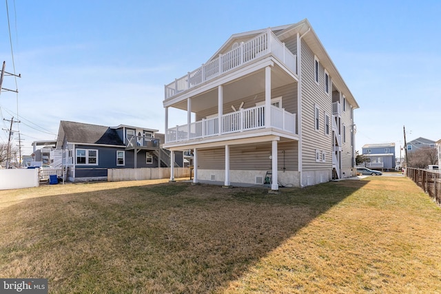 rear view of house featuring a lawn and fence