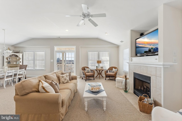 living room featuring a tiled fireplace, vaulted ceiling, a ceiling fan, and a wealth of natural light