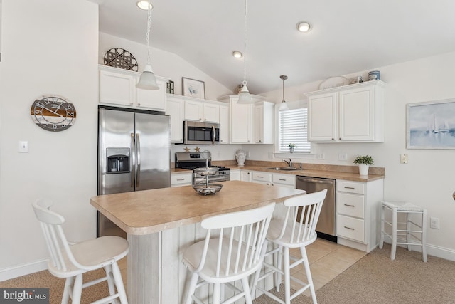 kitchen with a sink, a kitchen bar, appliances with stainless steel finishes, and white cabinetry