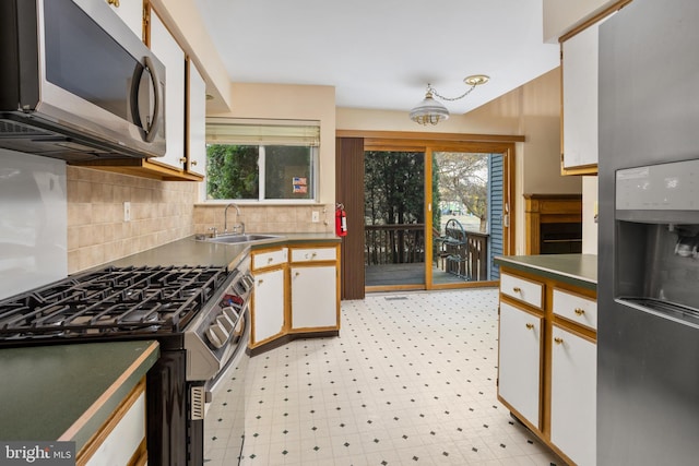 kitchen featuring a sink, dark countertops, stainless steel appliances, decorative backsplash, and light floors