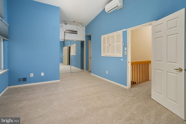 unfurnished bedroom with a wall mounted air conditioner, visible vents, a closet, carpet floors, and rail lighting