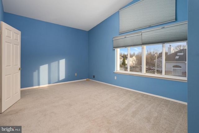 empty room with lofted ceiling, baseboards, and carpet floors