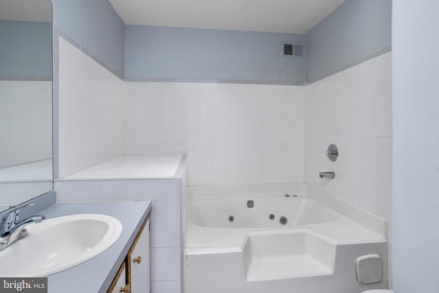 bathroom with visible vents, vanity, and a tub with jets