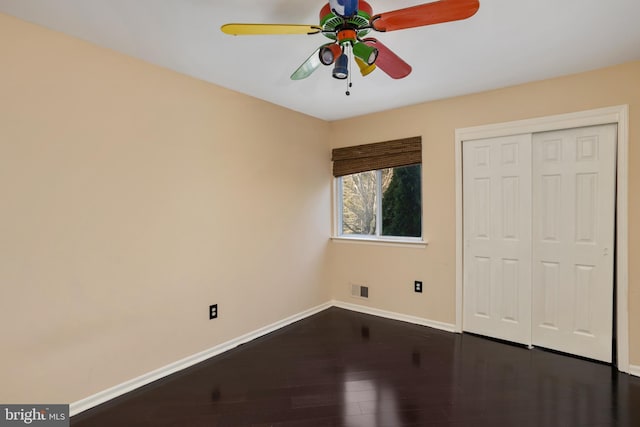 unfurnished bedroom featuring baseboards, visible vents, ceiling fan, dark wood-type flooring, and a closet