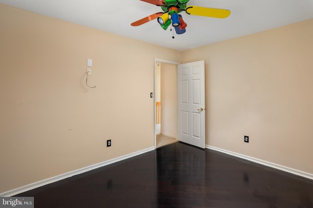 empty room with baseboards, dark wood-type flooring, and ceiling fan