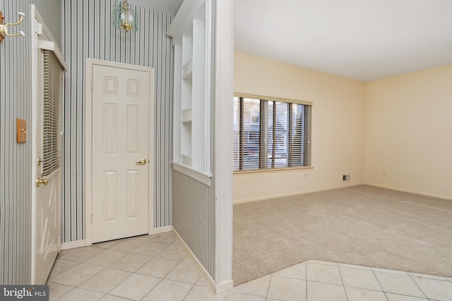 entryway featuring light tile patterned floors, light colored carpet, and baseboards