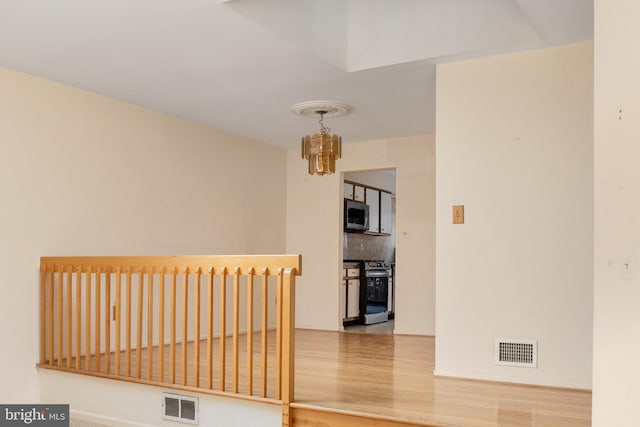 spare room with visible vents, an inviting chandelier, and wood finished floors