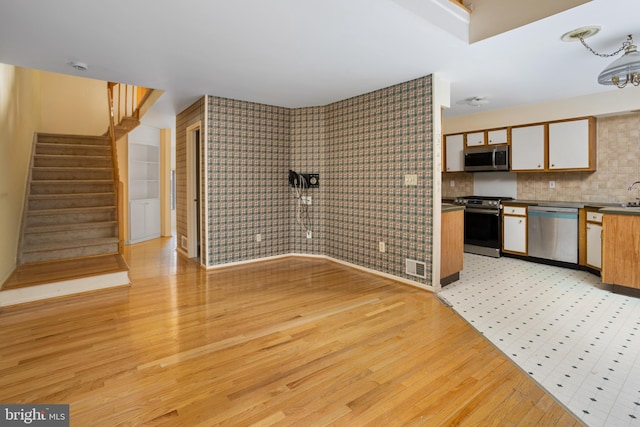 kitchen with light wood finished floors, visible vents, dark countertops, appliances with stainless steel finishes, and a sink