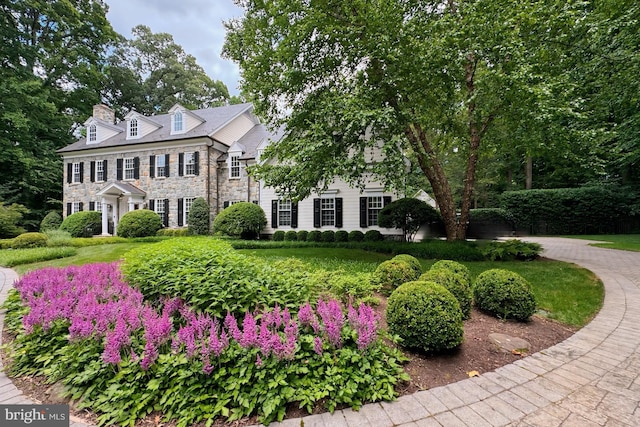 view of front of home with stone siding and a chimney