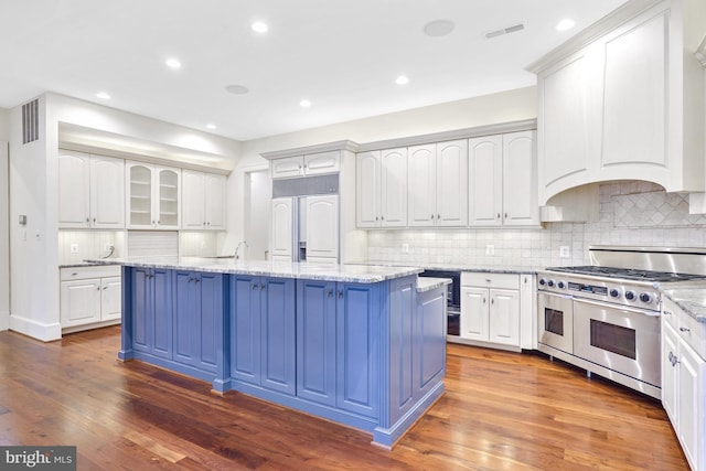 kitchen with blue cabinets, visible vents, high quality appliances, and white cabinets