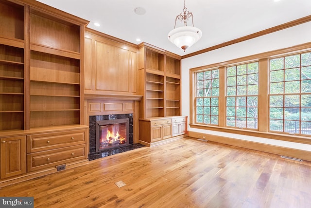 unfurnished living room with visible vents, baseboards, a fireplace, light wood-style floors, and crown molding