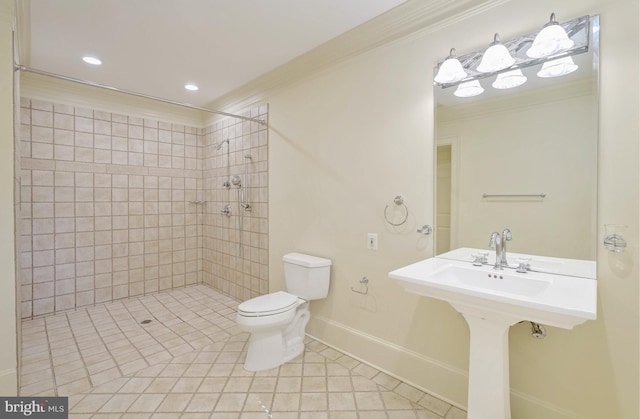 bathroom featuring toilet, ornamental molding, a tile shower, tile patterned flooring, and baseboards