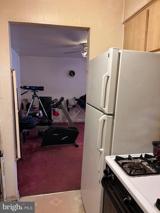 kitchen with gas range, a ceiling fan, and freestanding refrigerator