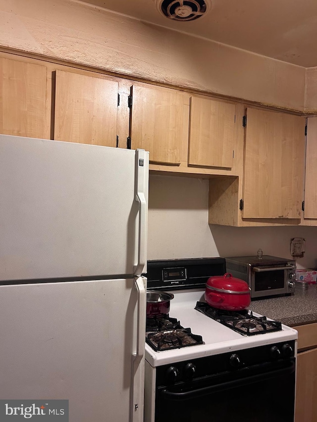 kitchen with range with gas cooktop, a toaster, and freestanding refrigerator