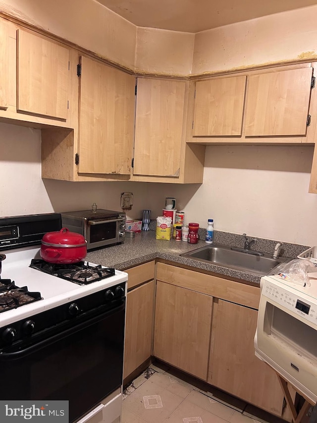 kitchen featuring a toaster, a sink, light brown cabinetry, and gas range oven