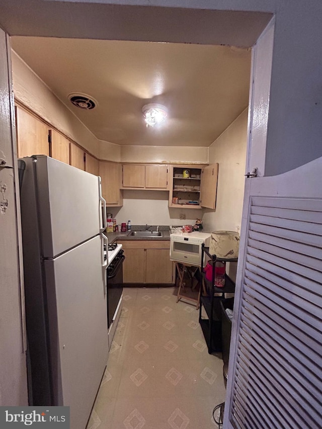 kitchen with white appliances, light floors, visible vents, light brown cabinetry, and a sink