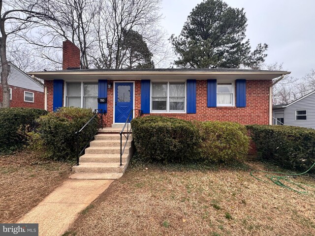 view of front of house featuring brick siding and a chimney