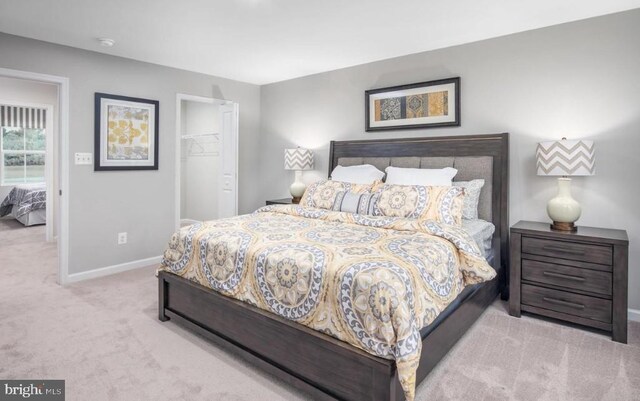 carpeted bedroom featuring a walk in closet, baseboards, and a closet