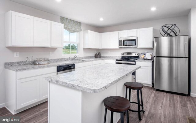 kitchen featuring wood finished floors, appliances with stainless steel finishes, a breakfast bar, and a center island