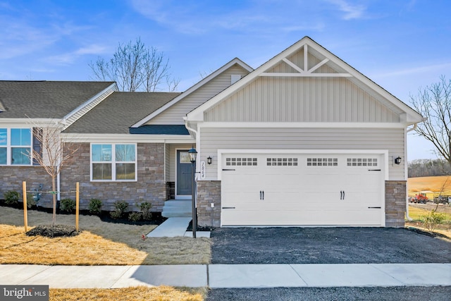 craftsman-style home featuring board and batten siding, an attached garage, stone siding, and driveway