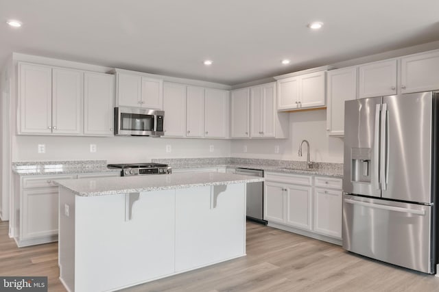 kitchen featuring light wood finished floors, a kitchen island, recessed lighting, appliances with stainless steel finishes, and white cabinetry