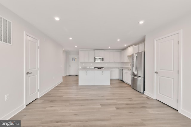 kitchen featuring a kitchen island, light wood-style flooring, light countertops, white cabinets, and appliances with stainless steel finishes