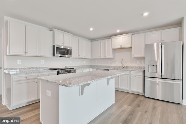 kitchen featuring a center island, a breakfast bar area, light wood-type flooring, white cabinets, and stainless steel appliances