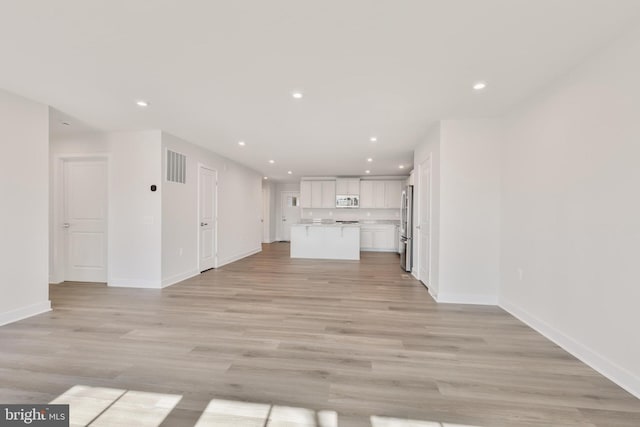 unfurnished living room with light wood-style flooring, recessed lighting, visible vents, and baseboards