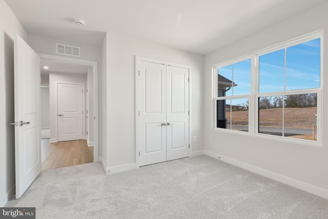 unfurnished bedroom featuring visible vents, baseboards, carpet, and a closet