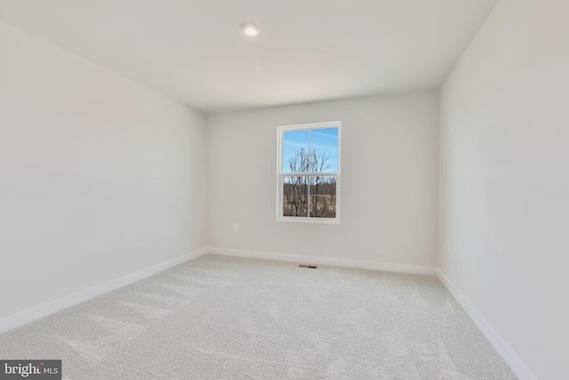 spare room with visible vents, light colored carpet, and baseboards