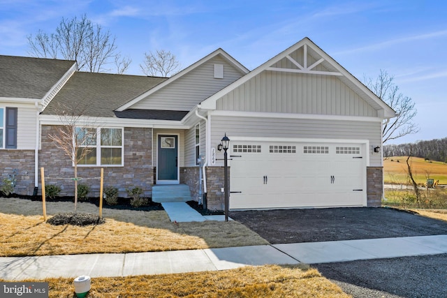 craftsman-style home featuring driveway, entry steps, stone siding, board and batten siding, and a garage