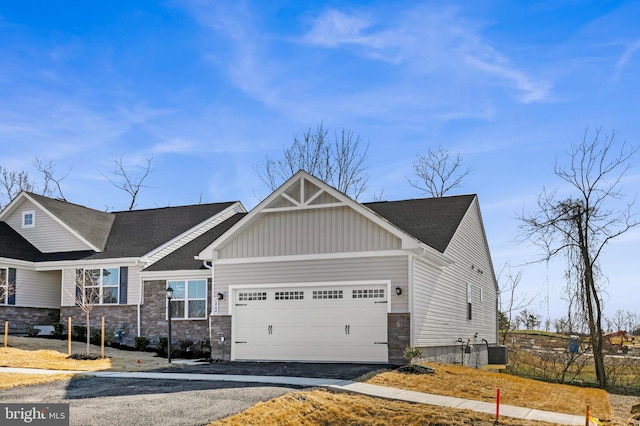 view of front of home featuring aphalt driveway, stone siding, a garage, and board and batten siding