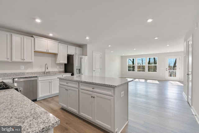 kitchen with a kitchen island, recessed lighting, white cabinets, appliances with stainless steel finishes, and light wood-type flooring