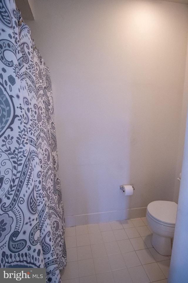 bathroom with tile patterned floors, toilet, and baseboards