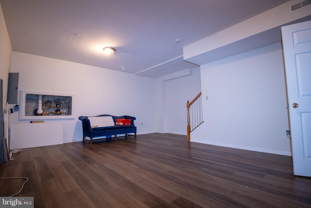 living area with visible vents, stairs, baseboards, and wood finished floors