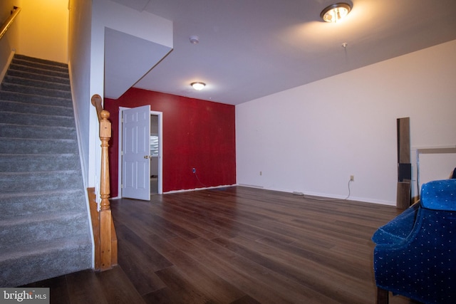 unfurnished living room featuring stairway, baseboards, and wood finished floors