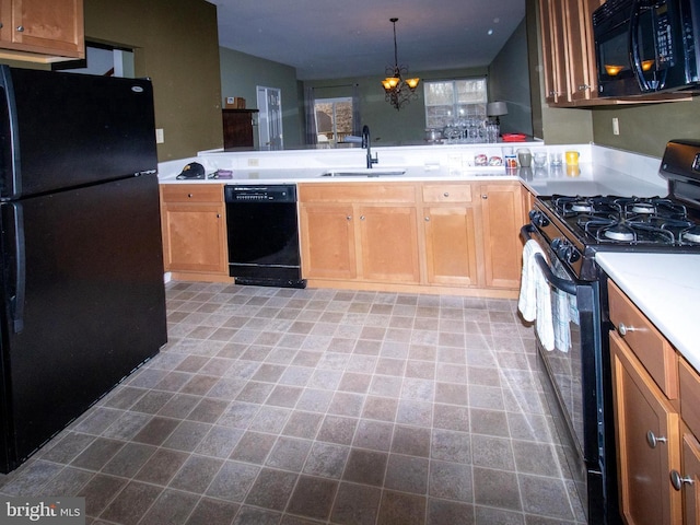 kitchen with an inviting chandelier, a sink, black appliances, light countertops, and decorative light fixtures